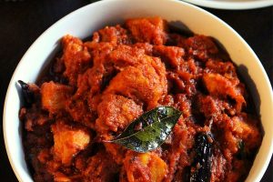 achari chicken served in a bowl with chapati beside