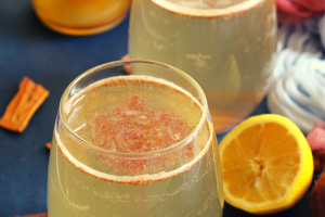 apple cider vinegar and honey drink with cinnamon is served in a glass with lemon