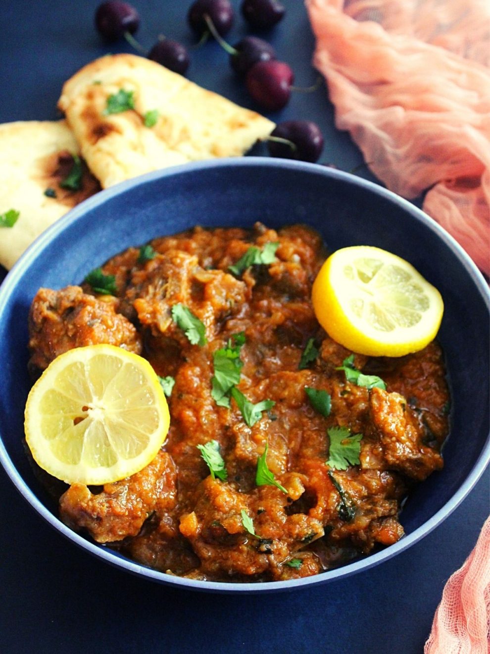 lamb karahi gosht served in a bowl with garnish of lemon wedges.