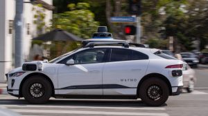 A Waymo autonomous vehicle operating on a tree-lined street in Santa Monica.