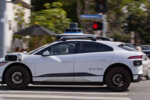 A Waymo autonomous vehicle operating on a tree-lined street in Santa Monica.