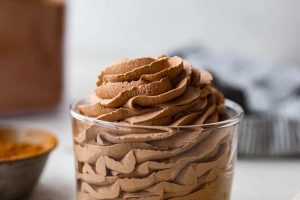 Side view of a glass with piped chocolate whipped cream inside.