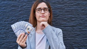 Woman holding money and thinking