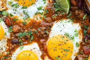 Overhead shot of a pot of breakfast chili with fried eggs on top.