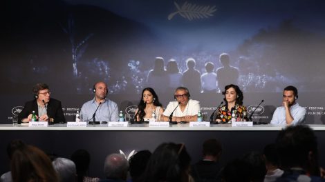 A group of people at a long table before microphones.