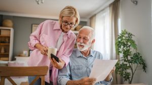 older couple looking at phone and paperwork