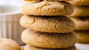 Side shot of browned butter sugar cookies stacked on a marble cutting board.