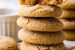 Side shot of browned butter sugar cookies stacked on a marble cutting board.