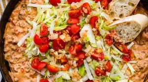 Overhead shot of cheeseburger dip topped with lettuce and tomatoes.