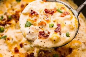 Overhead shot of a ladle filled with crock pot crack potato soup.