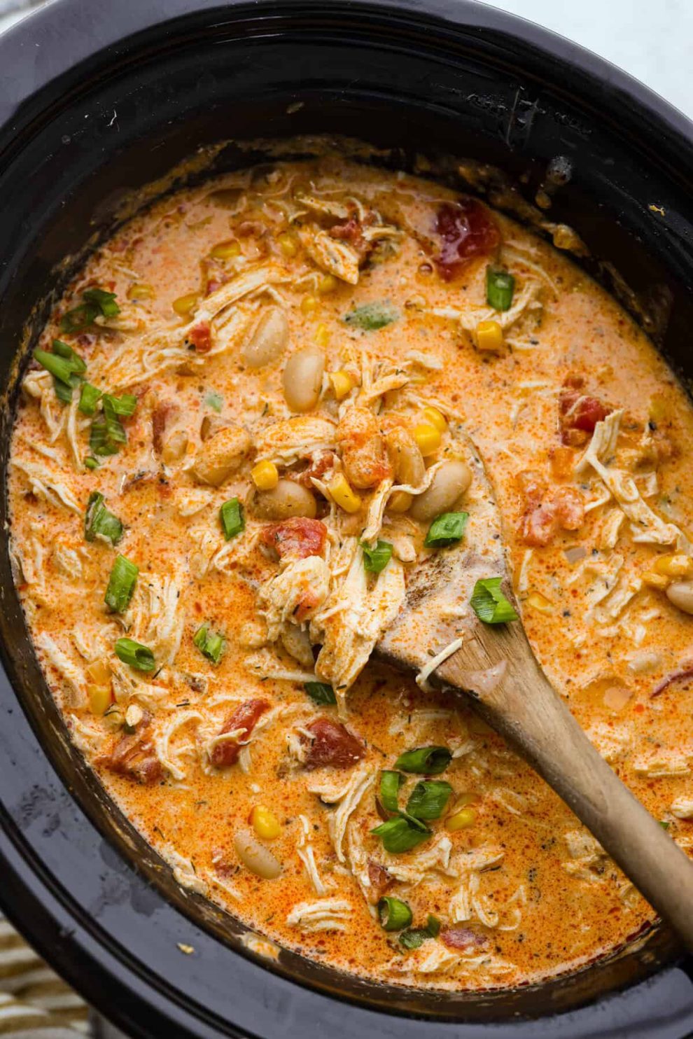 Overhead shot of crockpot buffalo chicken chili with a wooden spoon.