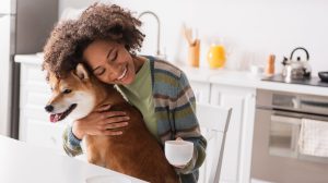 Woman holding her dog while drinking coffee