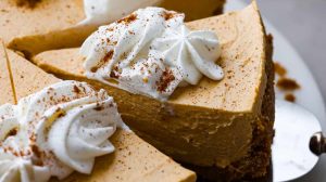 Angle shot of someone taking a slice of the no-bake pumpkin cheesecake with whipped cream on top.