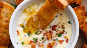 Overhead shot of shirred eggs in a ramekin surrounded by crostini.