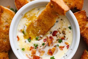 Overhead shot of shirred eggs in a ramekin surrounded by crostini.